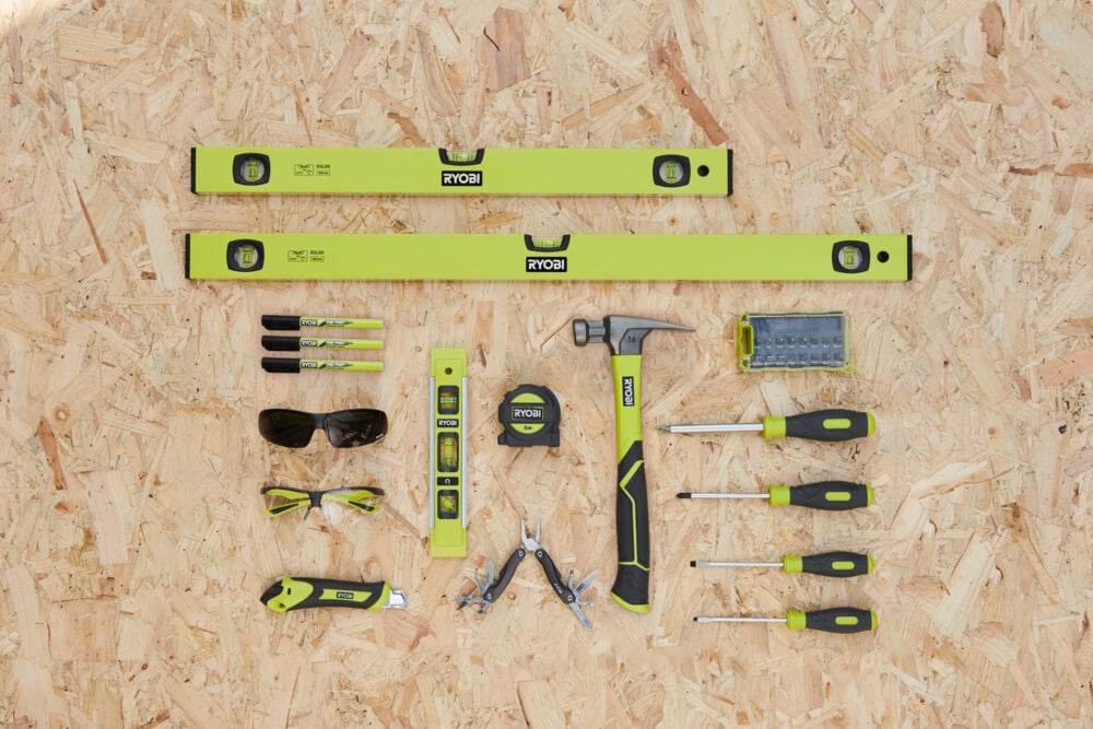 Podstawowe narzędzia do domu leżące na blacie roboczym: młotek, śrubokręty, metrówka, okulary ochronne, poziomica